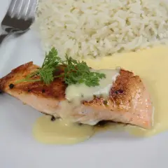 Un délicieux poisson sauce beurre blanc, servi avec du riz blanc et garni de persil frais.