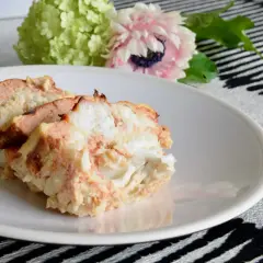 Tranches de terrine de lotte savoureuse sur une assiette blanche, avec des fleurs en arrière-plan.