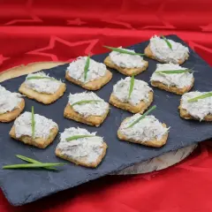 Douze toasts garnis de rillettes de maquereau, décorés d'une fine herbe verte, présentés sur une ardoise.