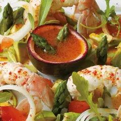 Délicieuse salade langoustine avec asperges, avocat et une sauce fruitée dans une demi-passiflore.