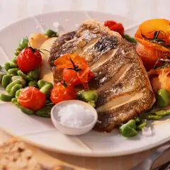 Filet de saint pierre grillé, servi avec des tomates cerises rôties et des fèves, un délice simple et savoureux.