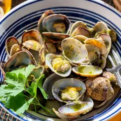 Tellines à la persillade dans un plat bleu et blanc, garnies de persil frais.