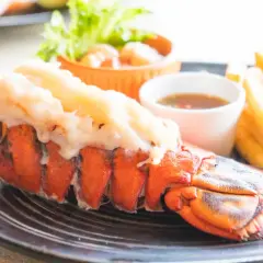 Un succulent homard grillé, accompagné de frites croustillantes, d'une sauce savoureuse et d'une touche de citron vert.