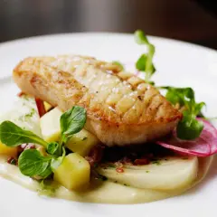 Filet d'églefin recette simple : poisson doré sur lit de purée, pommes de terre cubes, radis et jeunes pousses.