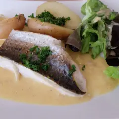 Filet de mulet poisson, servi avec des pommes de terre rôties, une salade verte et une sauce crémeuse.