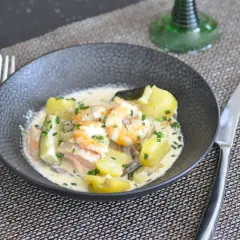 Un savoureux navarin de la mer avec crevettes, saumon, pommes de terre et courgettes, nappé d'une sauce crémeuse et garni de ciboulette.