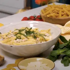 Un plat de pâtes au thon crémeuses, garni de menthe fraîche et de zeste de citron, prêt à être dégusté.