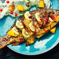 Poisson entier rôti, garni de tranches de kiwi, d'orange et de canneberges. Une belle recette poisson pour un repas festif.