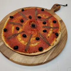Pizza à la sauce tomate, olives noires et anchois, prête à être dégustée. Une recette simple et savoureuse.