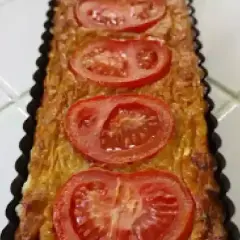 Quiche rectangulaire garnie de thon, tomate et moutarde, prête à être dégustée.