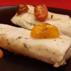 Deux filets de merlu au four, tendres et savoureux, ornés de tomates cerises rôties et d'aneth frais. Un délice simple et sain.