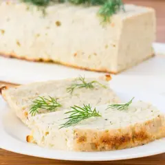 Tranche de terrine de poisson maison, garnie d'aneth frais, prête à être dégustée.
