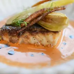 Un filet de poisson poêlé, garni de fenouil et de fines herbes, baignant dans un onctueux fumet de poisson orangé.