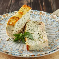 Deux tranches de pains de poisson, garnies d'herbes, sur une assiette décorée.