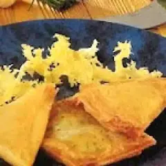 Délicieuse recette brick thon pomme de terre, croustillante et dorée, servie sur une assiette bleue avec une garniture jaune.