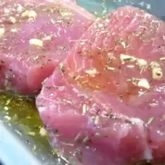 Deux beaux steaks de thon poisson marinés avec de l'ail et des herbes dans une huile dorée.