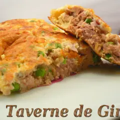 Une savoureuse omelette au thon et petits pois, coupée en deux pour révéler sa garniture généreuse. Un délice simple et rapide.