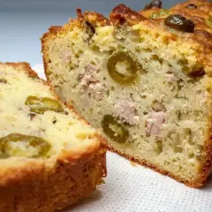 Tranche d'un cake au thon moelleux, garni d'olives vertes et de morceaux de thon. Parfait pour un apéritif ou un repas léger.