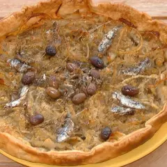 Pissaladière garnie d'anchois et d'olives, sur une pâte brisée ou feuilletée dorée.