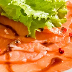 Délicieux carpaccio de saumon, fines tranches de poisson cru, garnies de quelques baies roses et d'une feuille de laitue croquante.