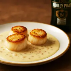 Trois noix de Saint-Jacques poêlées baignant dans une sauce onctueuse à la sauce Noilly Prat.