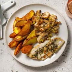 Filet de merlu poêlé, pommes de terre rôties et poêlée de champignons et poireaux. Le temps cuisson merlu poêle est parfait pour ce plat.