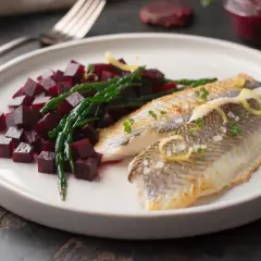 Deux filets de limande cardine poêlés, servis avec des dés de betterave et de la salicorne, garni de zestes de citron et de pousses vertes.