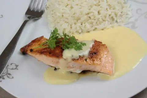 Un délicieux poisson sauce beurre blanc, servi avec du riz blanc et garni de persil frais.