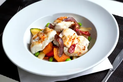 Délicieuse lotte poêlée, servie avec des légumes croquants et des tomates séchées. Un plat savoureux et coloré.