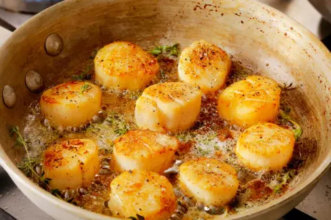 Poêlée de Saint-Jacques dorées, parsemées de poivre, dans du beurre mousseux avec du thym. Une recette coquille Saint-Jacques simple et savoureuse.