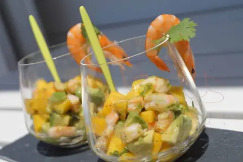 Verrine avocat saumon : deux coupes remplies d'un mélange coloré d'avocat, de mangue et de crevettes, garnies d'une crevette et d'une feuille de coriandre.