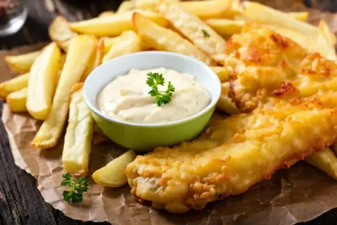 Poisson pané croustillant avec des frites dorées et une sauce crémeuse, parfait pour un repas savoureux.