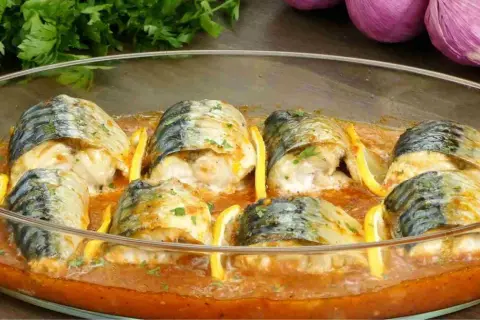 Maquereaux au four, tendres et savoureux, baignant dans une sauce tomate parfumée, accompagnés de quartiers de citron.