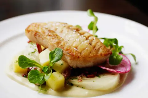 Filet d'églefin recette simple : poisson doré sur lit de purée, pommes de terre cubes, radis et jeunes pousses.