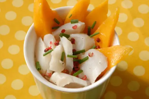 Délicieuse recette cabillaud enfant : morceaux de poisson blanc, mangue fraîche, ciboulette et poivre rose dans un bol.