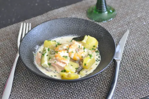 Un savoureux navarin de la mer avec crevettes, saumon, pommes de terre et courgettes, nappé d'une sauce crémeuse et garni de ciboulette.