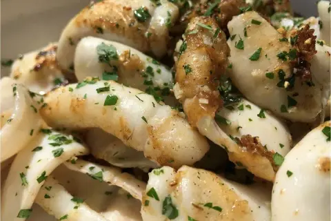 Délicieuse seiche à la plancha, dorée et parsemée de persil frais. Un plat simple et savoureux.