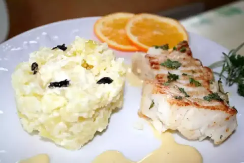 Dos de cabillaud poêlé, purée de pommes de terre aux olives, garni de sauce maltaise et de rondelles d'orange.