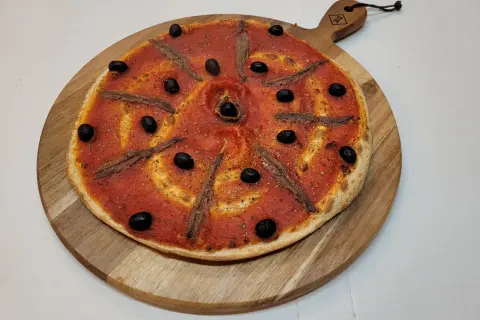 Pizza à la sauce tomate, olives noires et anchois, prête à être dégustée. Une recette simple et savoureuse.