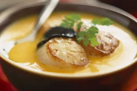 Velouté de butternut avec saint jacques poêlées, garni de persil et d'une touche de truffe.