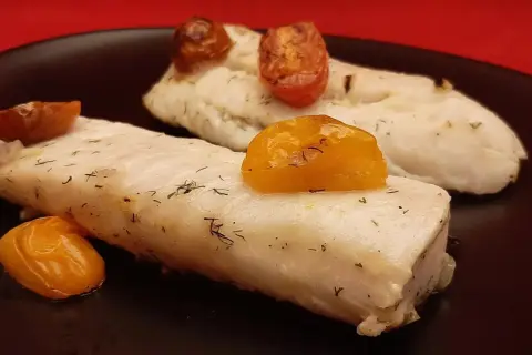 Deux filets de merlu au four, tendres et savoureux, ornés de tomates cerises rôties et d'aneth frais. Un délice simple et sain.