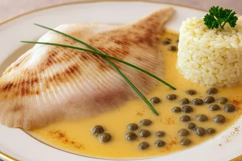 Délicieuse recette raie à la poêle, servie avec du riz et une sauce crémeuse aux câpres.