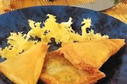 Délicieuse recette brick thon pomme de terre, croustillante et dorée, servie sur une assiette bleue avec une garniture jaune.