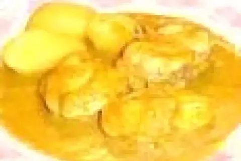 Un plat de bourride de lotte, avec des morceaux de poisson dans une sauce dorée et des pommes de terre.