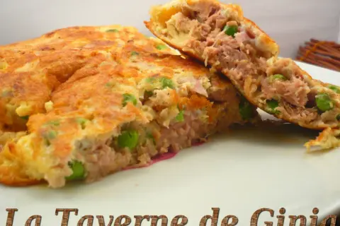 Une savoureuse omelette au thon et petits pois, coupée en deux pour révéler sa garniture généreuse. Un délice simple et rapide.