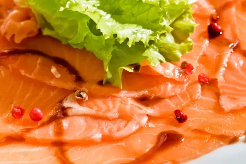 Délicieux carpaccio de saumon, fines tranches de poisson cru, garnies de quelques baies roses et d'une feuille de laitue croquante.