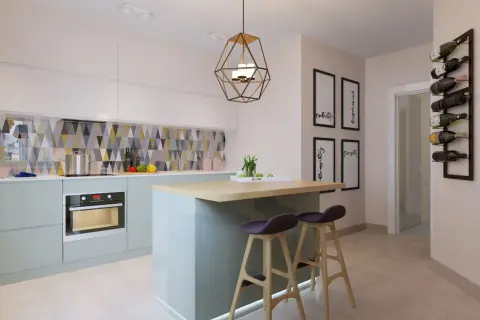 Cuisine moderne avec îlot central, tabourets et un bar à poisson mural.