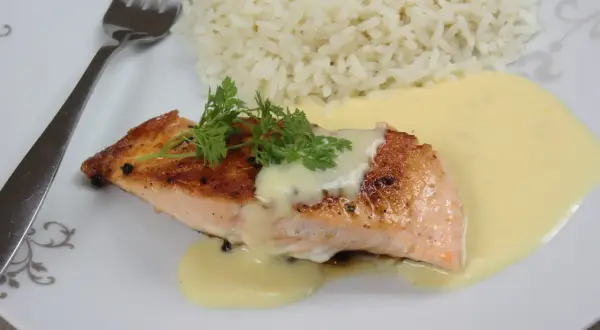 Un délicieux poisson sauce beurre blanc, servi avec du riz blanc et garni de persil frais.