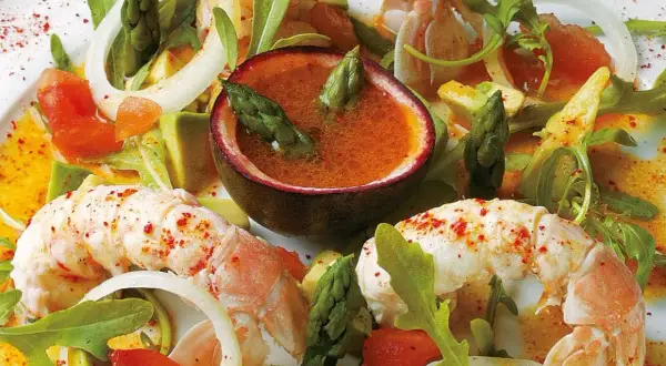 Délicieuse salade langoustine avec asperges, avocat et une sauce fruitée dans une demi-passiflore.