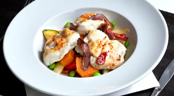Délicieuse lotte poêlée, servie avec des légumes croquants et des tomates séchées. Un plat savoureux et coloré.